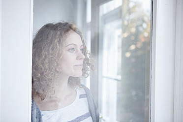 Deutschland, Bayern, München,Junge Frau schaut aus dem Fenster - RBF001142