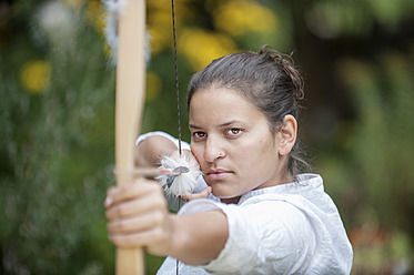 Austria, Salzburg Country, Young woman aiming arrow, close up - HHF004336