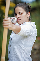 Austria, Salzburg Country, Young woman aiming arrow, close up - HHF004337