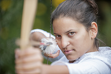 Austria, Salzburg Country, Young woman aiming arrow, close up - HHF004338