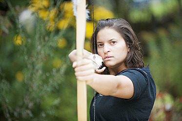 Austria, Salzburg Country, Young woman aiming arrow, close up - HHF004345