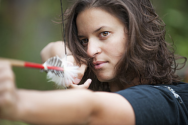 Austria, Salzburg Country, Young woman aiming arrow, close up - HHF004348