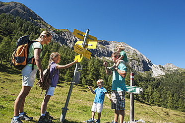 Österreich, Salzburg, Familie schaut auf Wegweiser in Altenmarkt Zauchensee - HHF004364