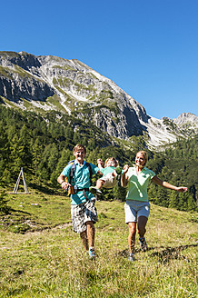 Österreich, Salzburg, Eltern spazieren und schaukelnder Sohn auf Bergen in Altenmarkt Zauchensee - HHF004367
