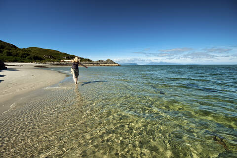 UK, Schottland, Ältere Frau geht am Strand spazieren, lizenzfreies Stockfoto