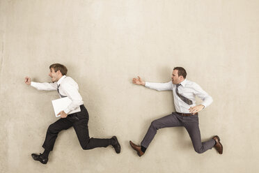 Businessmen chasing against beige background - BAEF000403