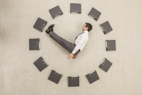 Businessman inside circle of files forming clock - BAEF000465