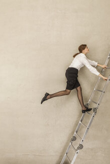 Businesswoman climbing ladder in office - BAEF000521