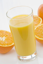 Glas Orangensaft neben Orangen auf weißem Hintergrund, Nahaufnahme - ASF004845
