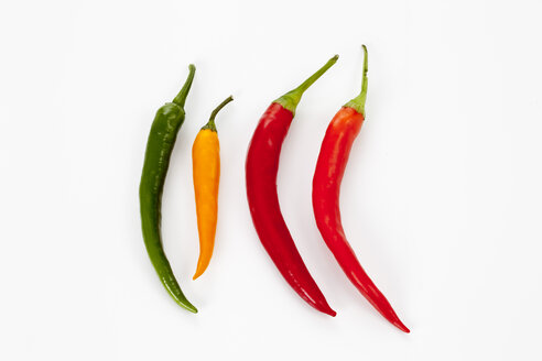 Red, orange and green chili peppers on white background, close up - CSF016694