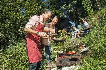 Österreich, Salzburger Land, Mann kocht für seine Familie im Garten - HHF004409