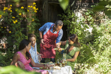 Österreich, Salzburger Land, Mann bedient seine Familie im Garten - HHF004425