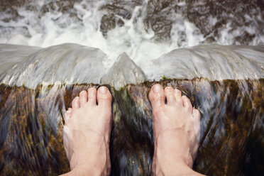 Austria, Barefooted man standing at edge of waterfall - WVF000322