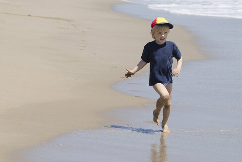 Spain, Boy with peaked cap running on beach - CWF000006