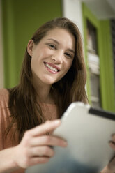 Germany, Bavaria, Munich, Portrait of young woman using digital tablet, smiling - RNF001104