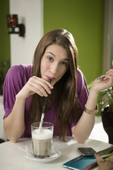 Germany, Bavaria, Munich, Portrait of young woman enjoying coffee in cafe - RNF001108