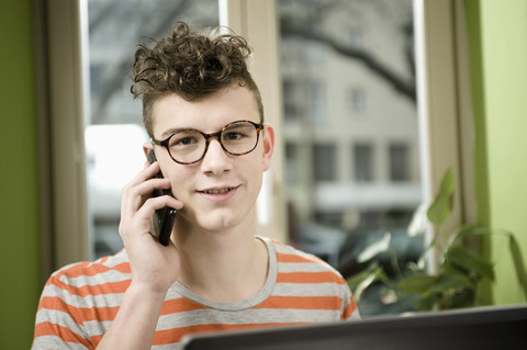 Deutschland, Bayern, München, Junger Mann, der in einem Café mit seinem Handy telefoniert, lizenzfreies Stockfoto