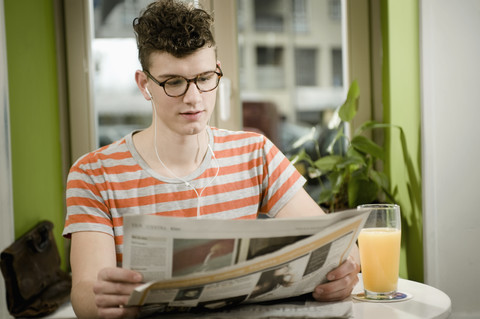 Deutschland, Bayern, München, Junger Mann liest Zeitung in einem Cafe, lizenzfreies Stockfoto