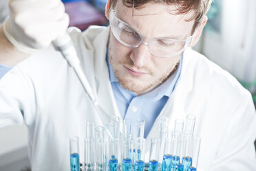Deutschland, Junge Wissenschaftlerin pipettiert blaue Flüssigkeit in Reagenzgläser, Nahaufnahme - FLF000265