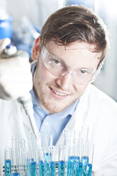 Deutschland, Junge Wissenschaftlerin pipettiert blaue Flüssigkeit in Reagenzgläser, Nahaufnahme - FLF000266