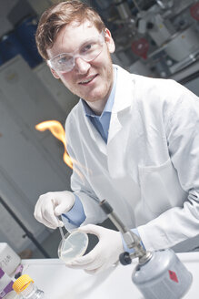 Germany, Young scientist examining bacteria in petri desh - FLF000291