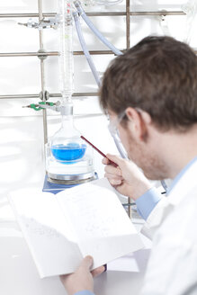 Germany, Portrait of young scientist making notes about chemical process, smiling - FLF000307