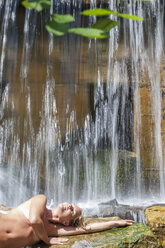 Österreich, Altenmarkt-Zauchensee, Mittlere erwachsene Frau entspannt sich am Wasserfall - HHF004456