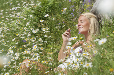 Österreich, Salzburg, Mittlere erwachsene Frau mit Blumen auf einer Wiese, lächelnd - HHF004470