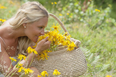 Austria, Altenmarkt-Zauchensee, Mid adult woman in alpine meadow with arnica - HHF004479