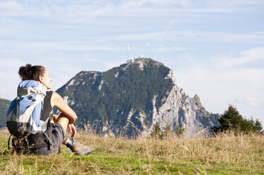 Deutschland, Bayern, Mittlere erwachsene Frau sitzt auf einer Wiese und schaut zum Wendelstein - UMF000592