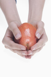 Human hands holding pear against white background, close up - CRF002296