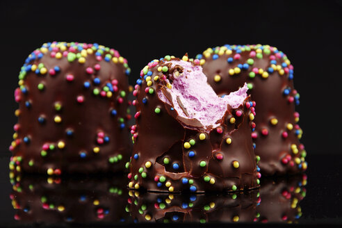 Schokoladen-Marshmallow mit Zuckerperlen auf schwarzem Grund, Nahaufnahme - HOHF000063
