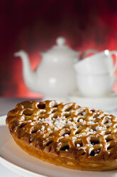 Gittertorte mit Kirschen und Zuckerkristallen und Teekanne im Hintergrund - CSF017360