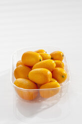 Plastikdose mit Kumquats auf weißem Hintergrund, Nahaufnahme - CSF017496