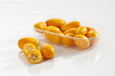 Plastikdose mit Kumquats auf weißem Hintergrund, Nahaufnahme - CSF017495