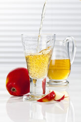 Carafe and glass with pouring apple juice, close up - CSF017424