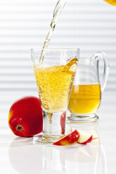 Carafe and glass with pouring apple juice, close up - CSF017423