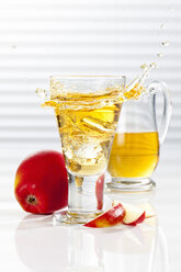 Carafe and glass with splashing apple juice, close up - CSF017421