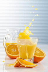 Karaffe und Glas mit spritzendem Orangensaft, Nahaufnahme - CSF017413