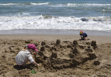 Spanien, Mädchen und Junge spielen am Strand im Sand - CWF000011