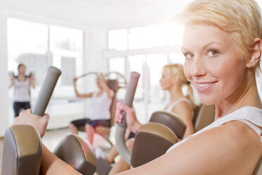Deutschland, Brandenburg, Frauen trainieren im Fitnessstudio, lächelnd - FKF000122