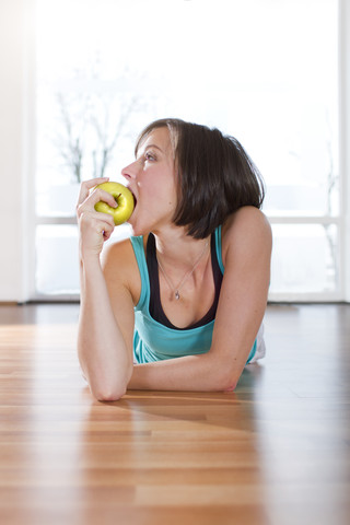 Deutschland, Brandenburg, Frau isst Apfel im Fitnessstudio, lizenzfreies Stockfoto