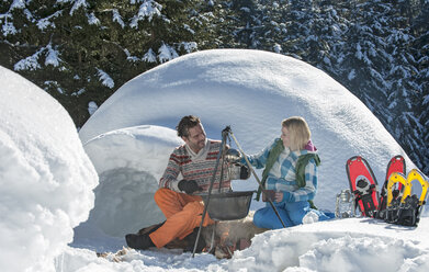 Austria, Salzburg, Couple preparing tea near igloo - HHF004539