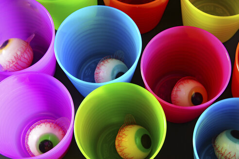 Colorful candy eyeballs in plastic cups, elevated view - HOHF000074