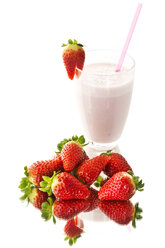 Glass of strawberry milk shake besides strawberries on white background, close up - MAEF006073