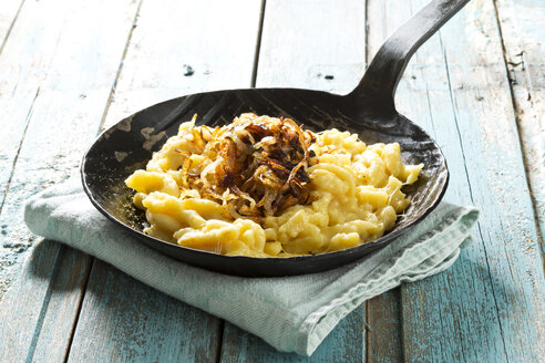 Spätzle mit Käse und Röstzwiebeln in der Pfanne auf dem Tisch, Nahaufnahme - MAEF006065