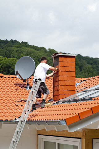 Europa, Deutschland, Rheinland Pfalz, Mann deckt Schornstein mit Dachschindeln ab, lizenzfreies Stockfoto
