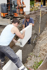 Europe, Germany, Rhineland Palatinate, Men installing corner stone in soil while house building - CSF017695