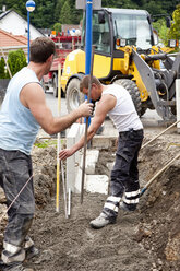 Europe, Germany, Rhineland Palatinate, Men installing corner stone in soil while house building - CSF017696