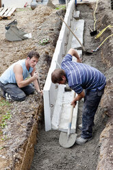 Europe, Germany, Rhineland Palatinate, Men installing corner stone in soil while house building - CSF017689